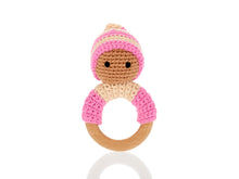 Load image into Gallery viewer, Pink wooden &amp; crochet teething ring rattles. The wood ring is half wrapped with crocheted cotton, a cute head sits on top of the wooden ring with stitched black eyes and a matching bobby hat